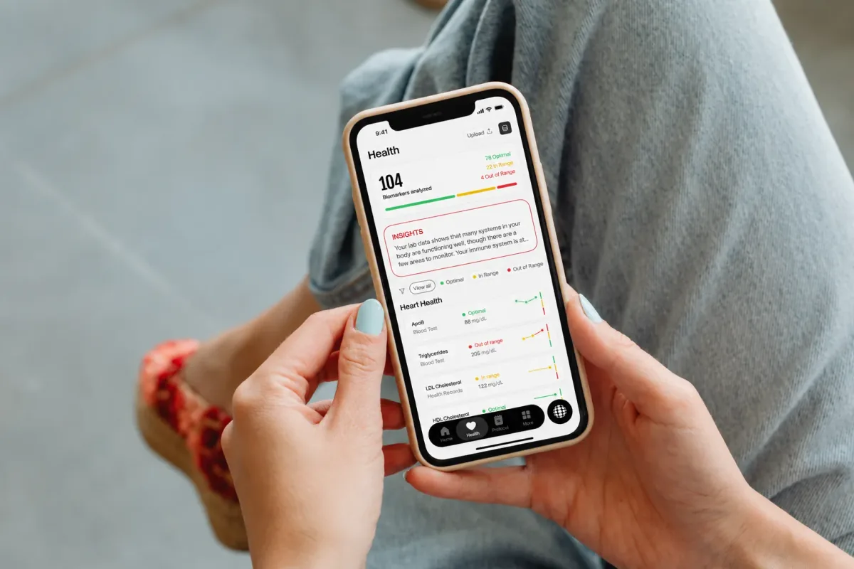 A person holding a phone that shows their Kurma health dashboard and biomarker results